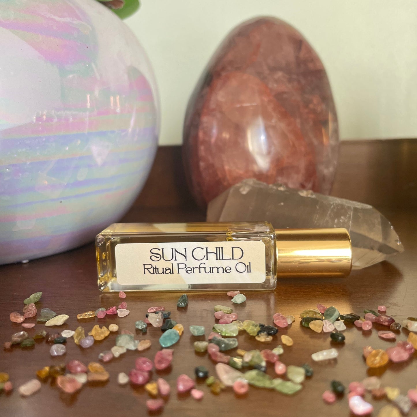 Perfume oil bottle labeled 'Sunchild' with crystals and stones on a neutral background