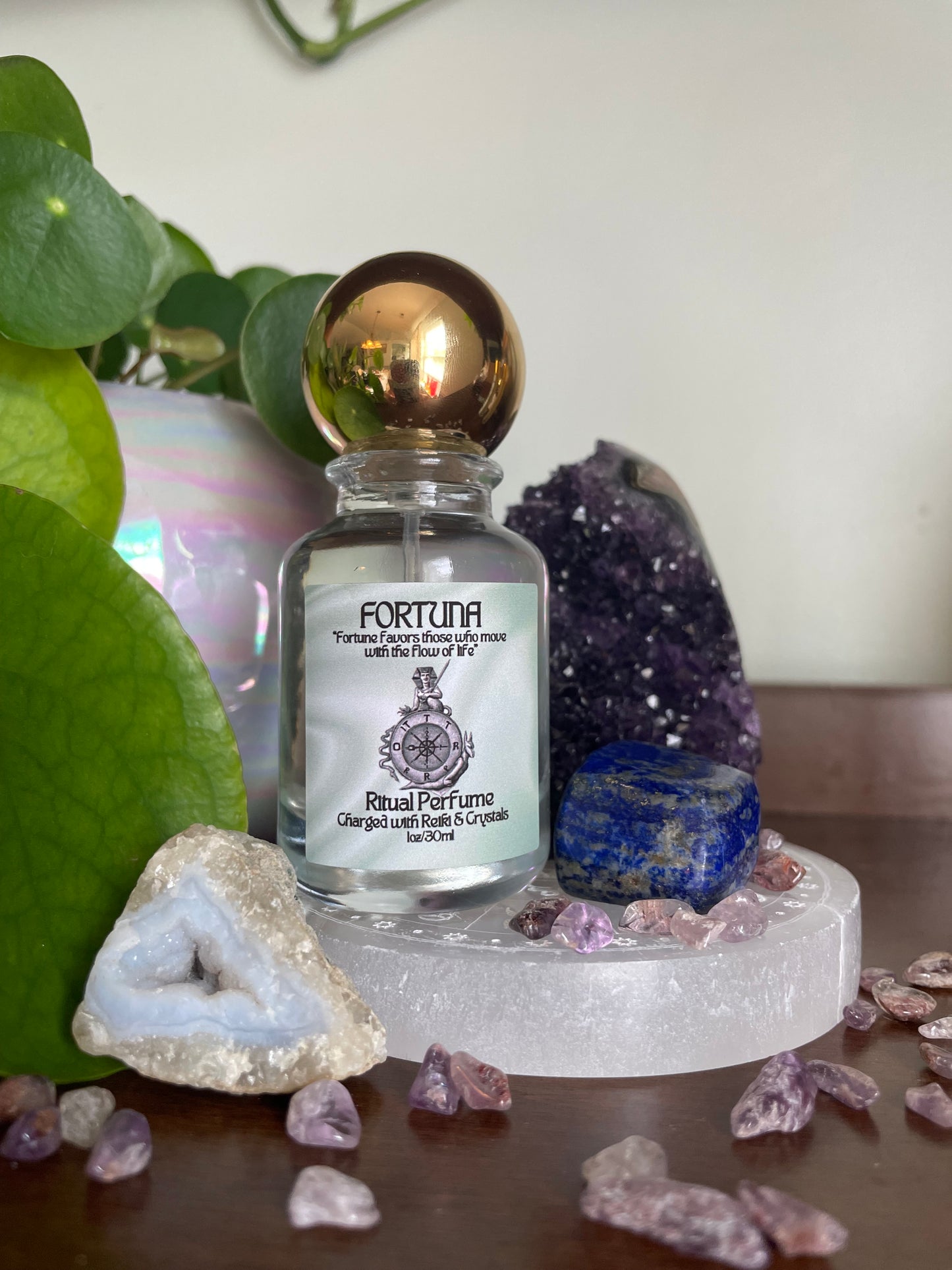 Small bottle labeled 'Fortuna' surrounded by crystals and gemstones on a white background
