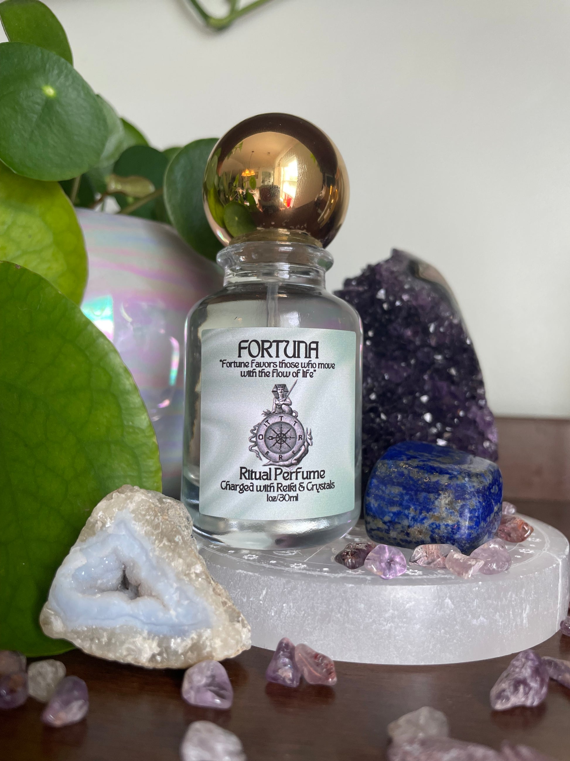 Small bottle labeled 'Fortuna' surrounded by crystals and gemstones on a white surface.