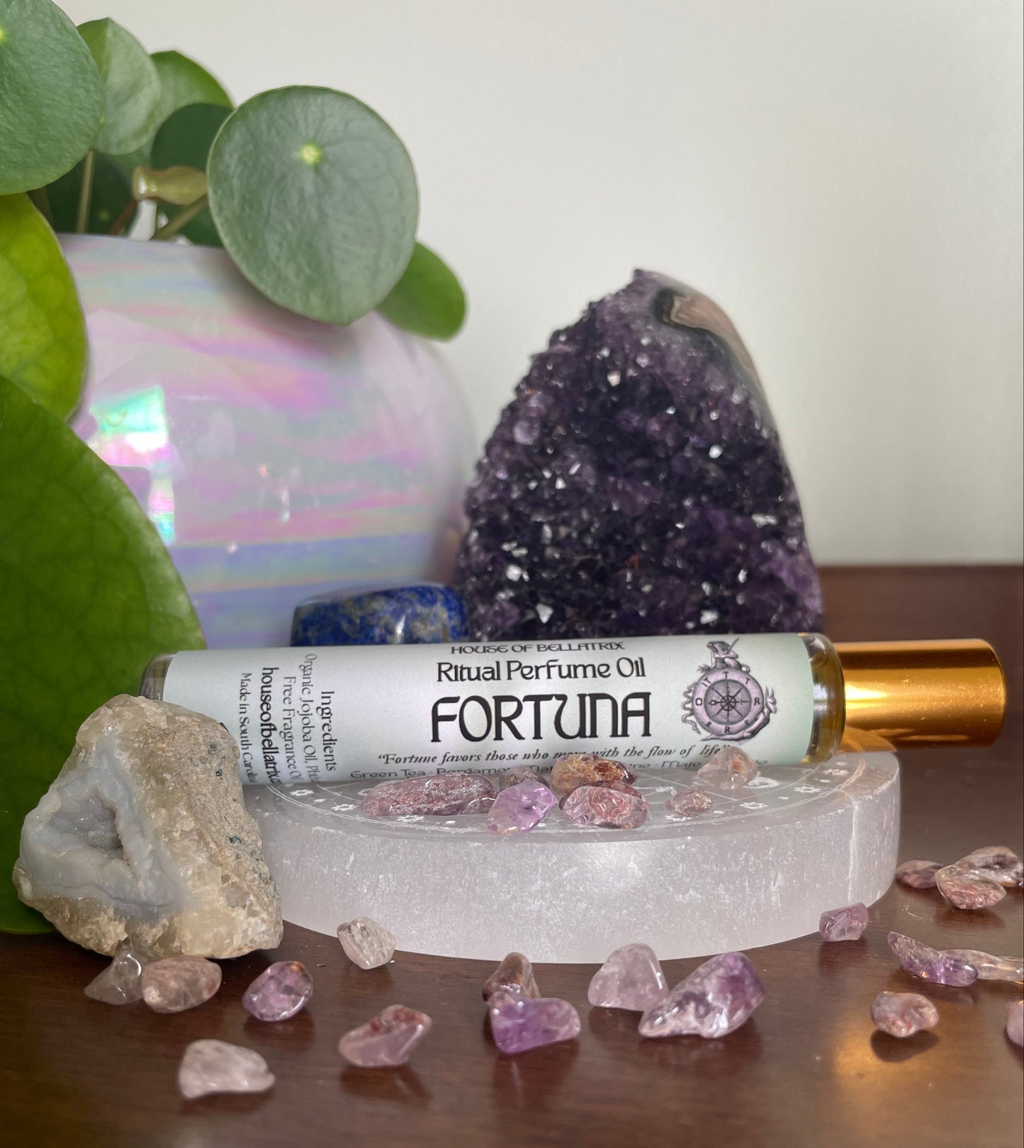 Fortuna perfume oil bottle with crystals and amethyst on a wooden surface